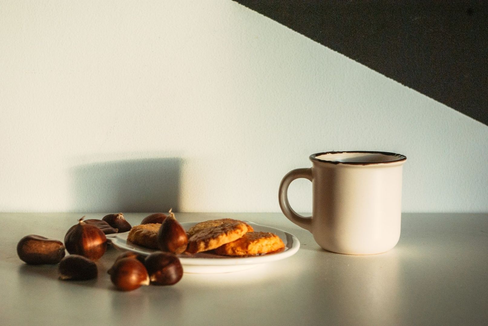 Kaffekopp och mördegskakor på fat, omgivna av hasselnötter